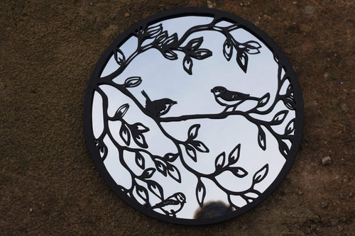 Circular cutout with black bird and branch design on a white background, placed on a textured brown surface.