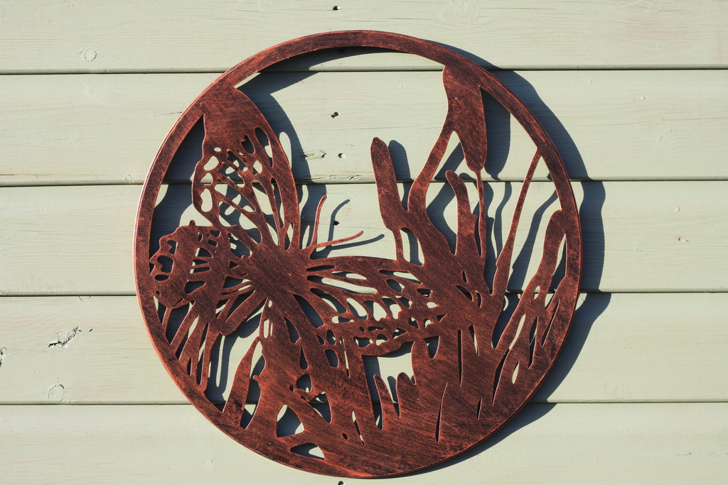 Decorative metal wall art with butterfly design on a wooden surface