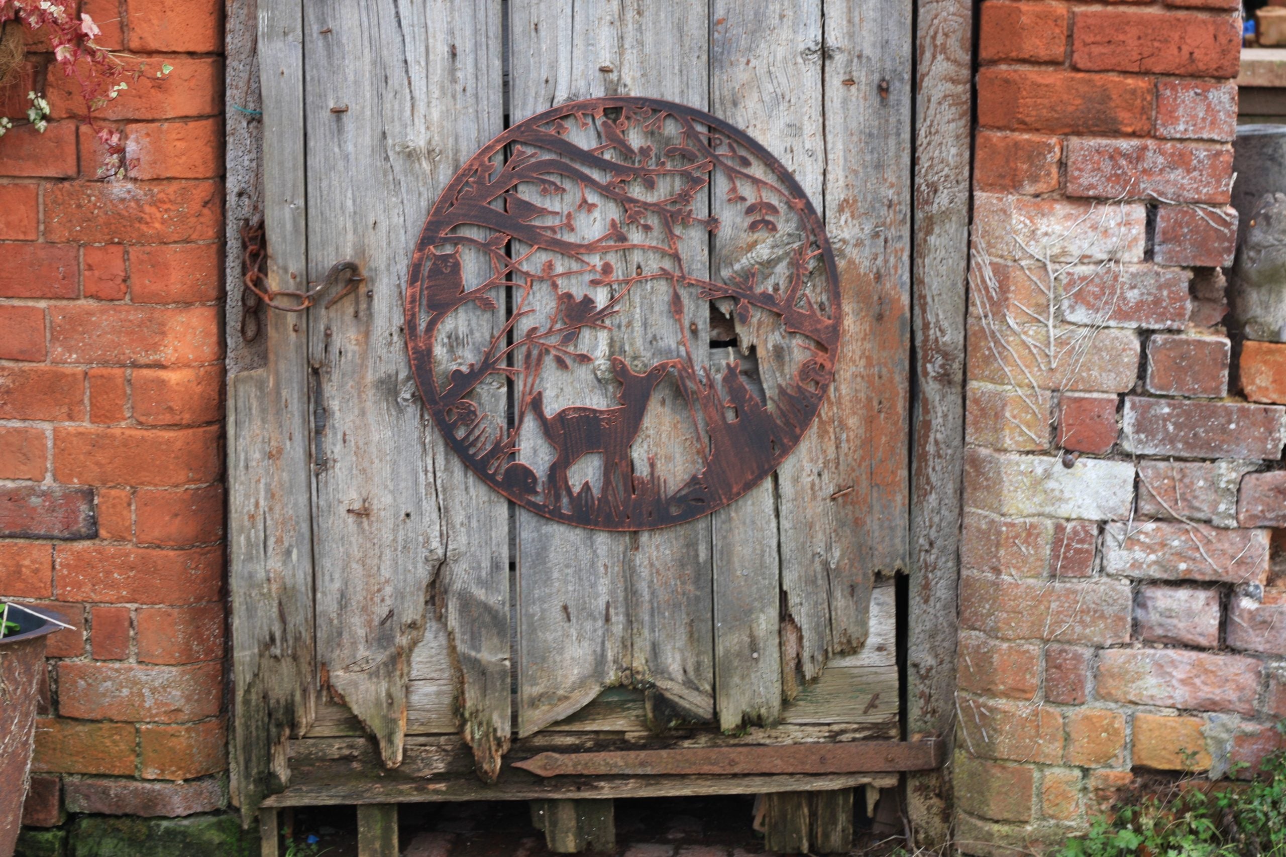 Rustic metal circular object on a wooden door with brick walls in the background