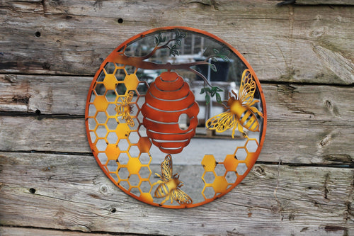 Decorative metal wall art with bees and a beehive on a wooden background