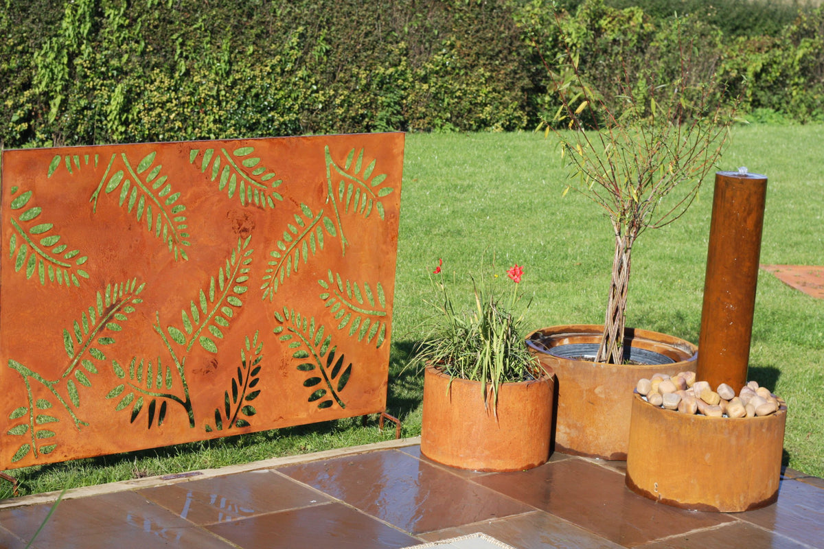 Decorative corten steel screen with leaf patterns in an outdoor setting.