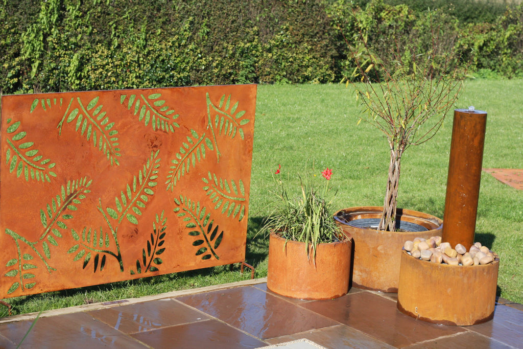 Decorative corten steel screen with leaf patterns in an outdoor setting.