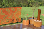 Decorative corten steel screen with leaf patterns in an outdoor setting.