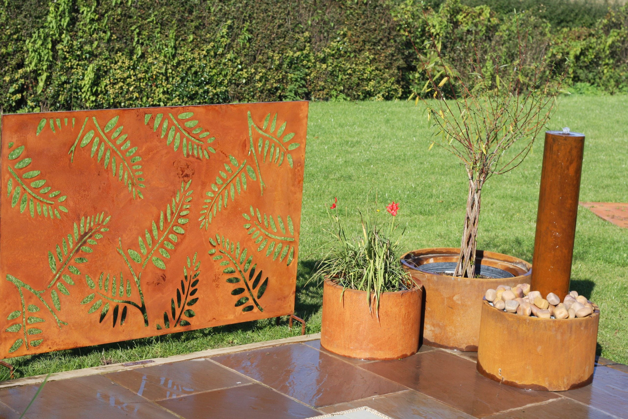 Decorative corten steel screen with leaf patterns in an outdoor setting.