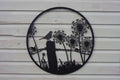 Decorative metal wall art with a bird and dandelions on a wooden background