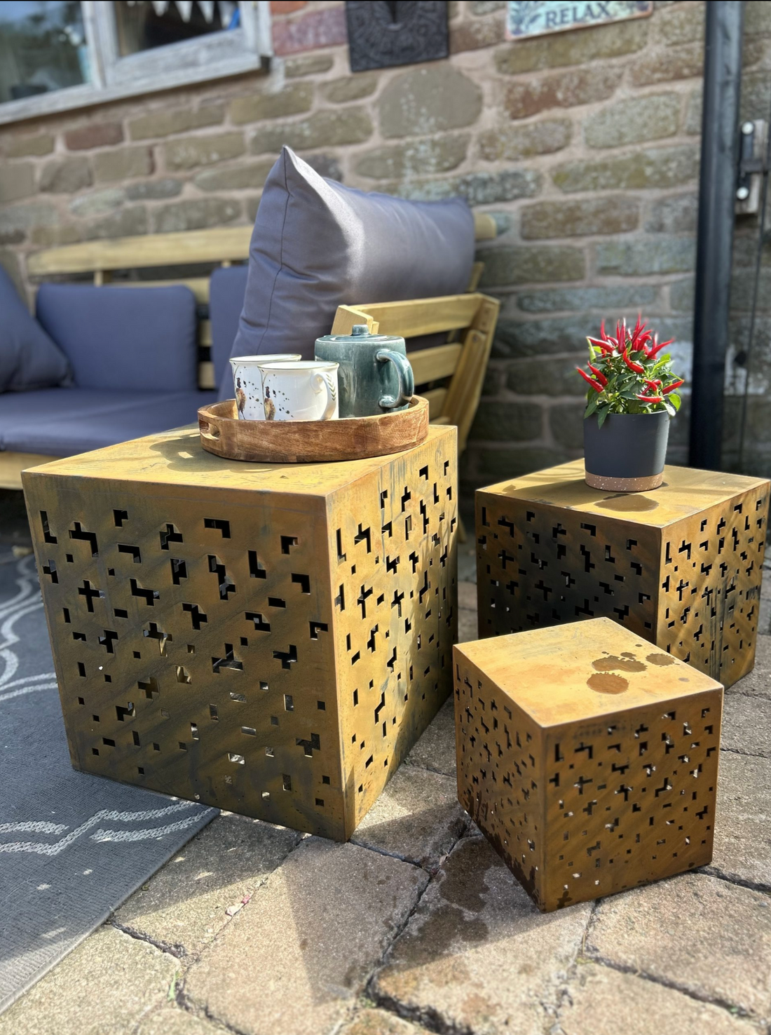 Outdoor patio set with laser-cut metal tables and a stone wall background